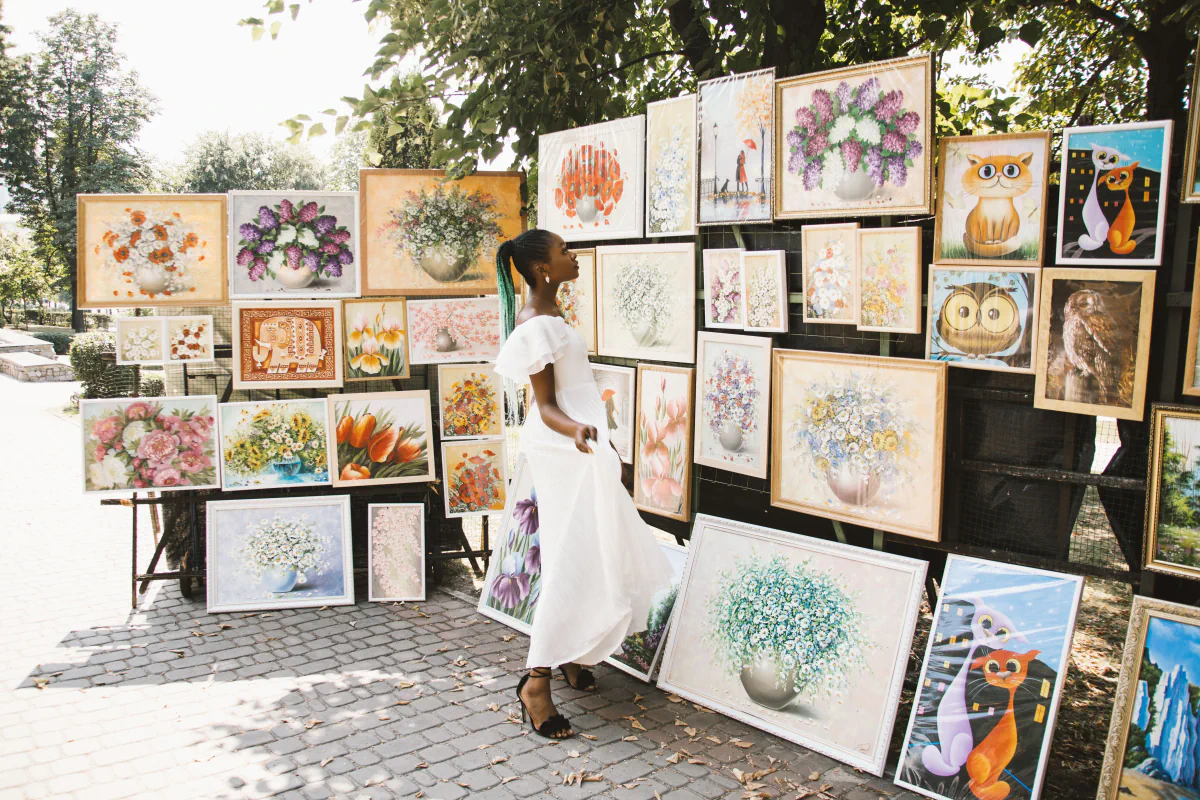 A visitor browsing paintings at an outdoor art market.